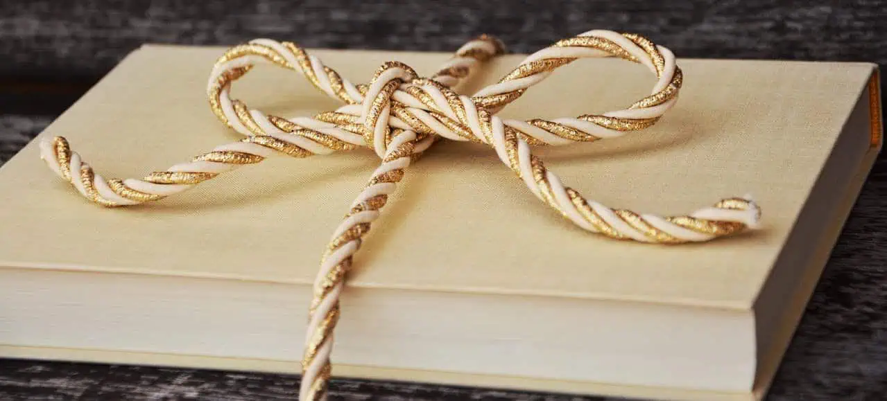 Soft beige gift box with gold and white twisted cord ribbon, elegant packaging and decoration for special occasions, luxury gift presentation, stylish and sophisticated gift wrapping for celebrations.