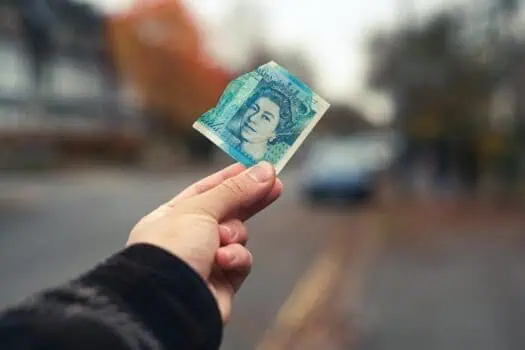 Five Pound Note Held Outdoors in Hand.