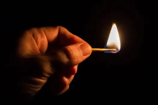 Matchstick igniting a small flame in darkness, symbolising hope, ignition, or change, with focus on hand and flame, relevant for social change, empowerment, or activism images from Prowess.