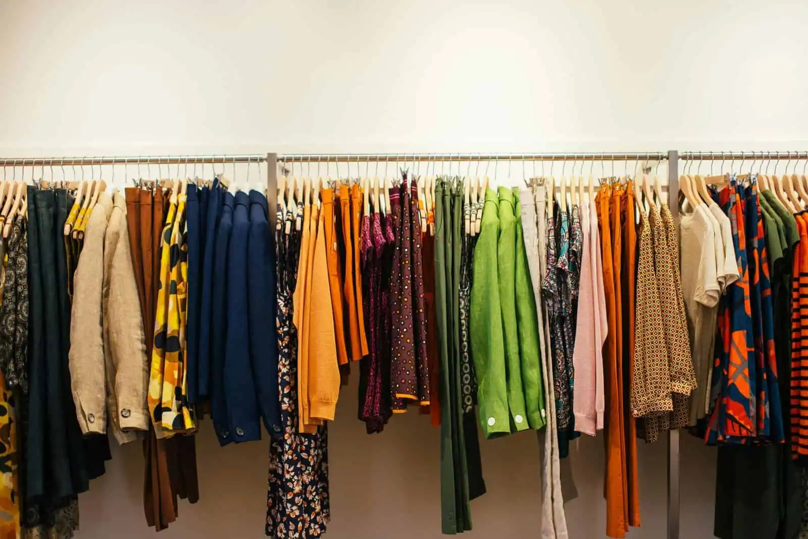 Brightly coloured clothing on a clothing rack at Prowess charity shop in the UK, supporting employment opportunities for disabled people, sustainable fashion, and community inclusion.
