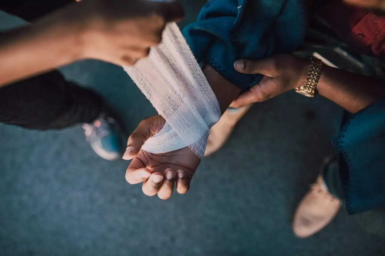 Victim with arm bandaged receiving care, symbolising support, compassion, and healing in a social or medical context. Focus on community aid, medical treatment, and humanitarian assistance.