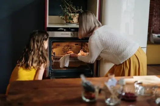 Learning activity of woman and girl cooking baking in modern kitchen.