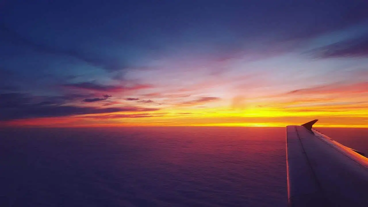Stunning sunset view from an airplane window with vibrant colours over the clouds.