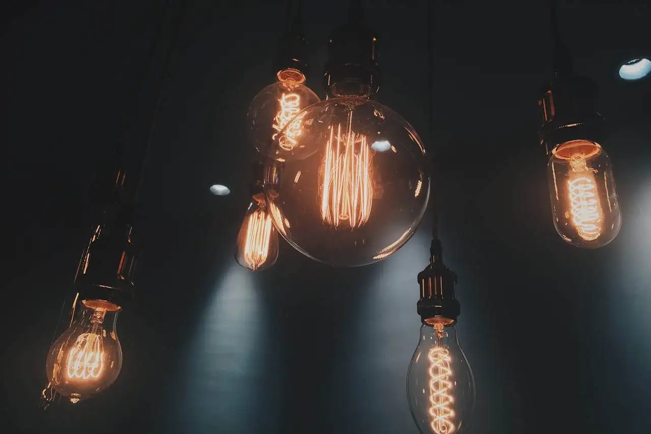 Vintage Edison filament light bulbs hanging in a dark room, creating warm ambient lighting. Stylish industrial lighting fixtures suitable for modern interiors, cafes, and home decor with a cosy atmosphere.