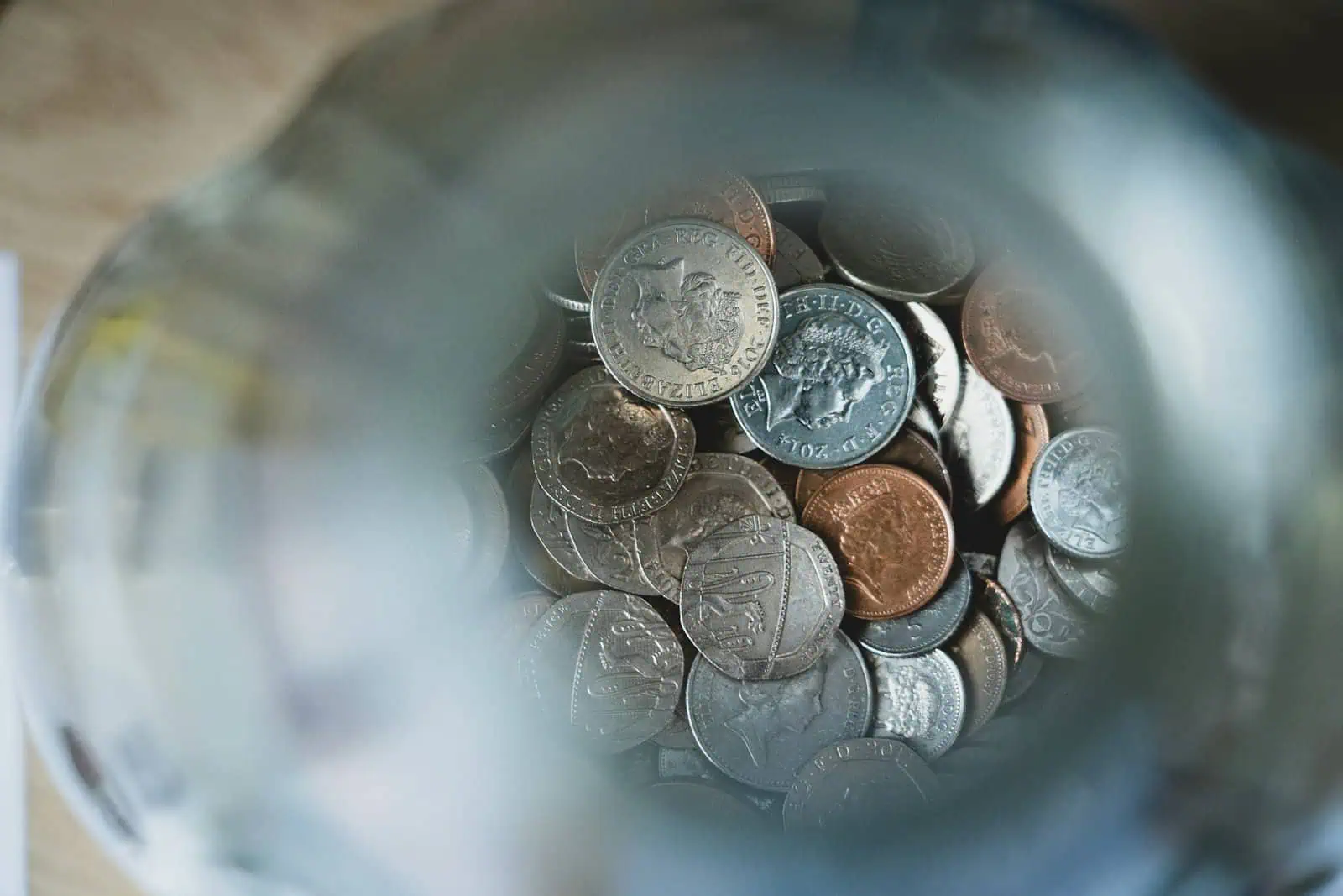 Loose UK coins inside a money jar, showcasing British currency, pennies, and coins.