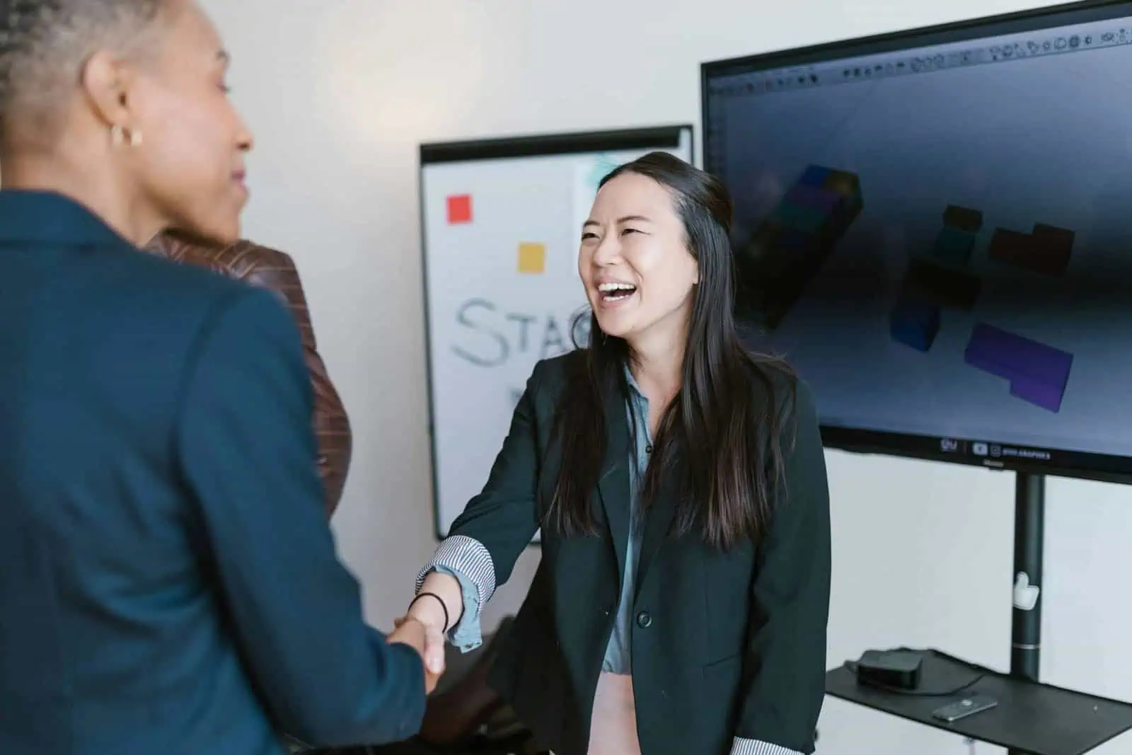 Motivated woman in business attire shaking hands with a colleague during a work meeting, professional networking, female empowerment, successful business interaction, modern office environment.