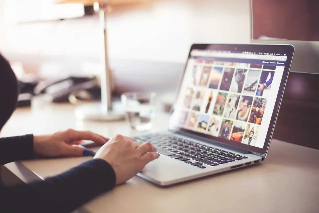 Images of a person using a laptop to browse social media or photo gallery, with natural light in an office or home workspace.