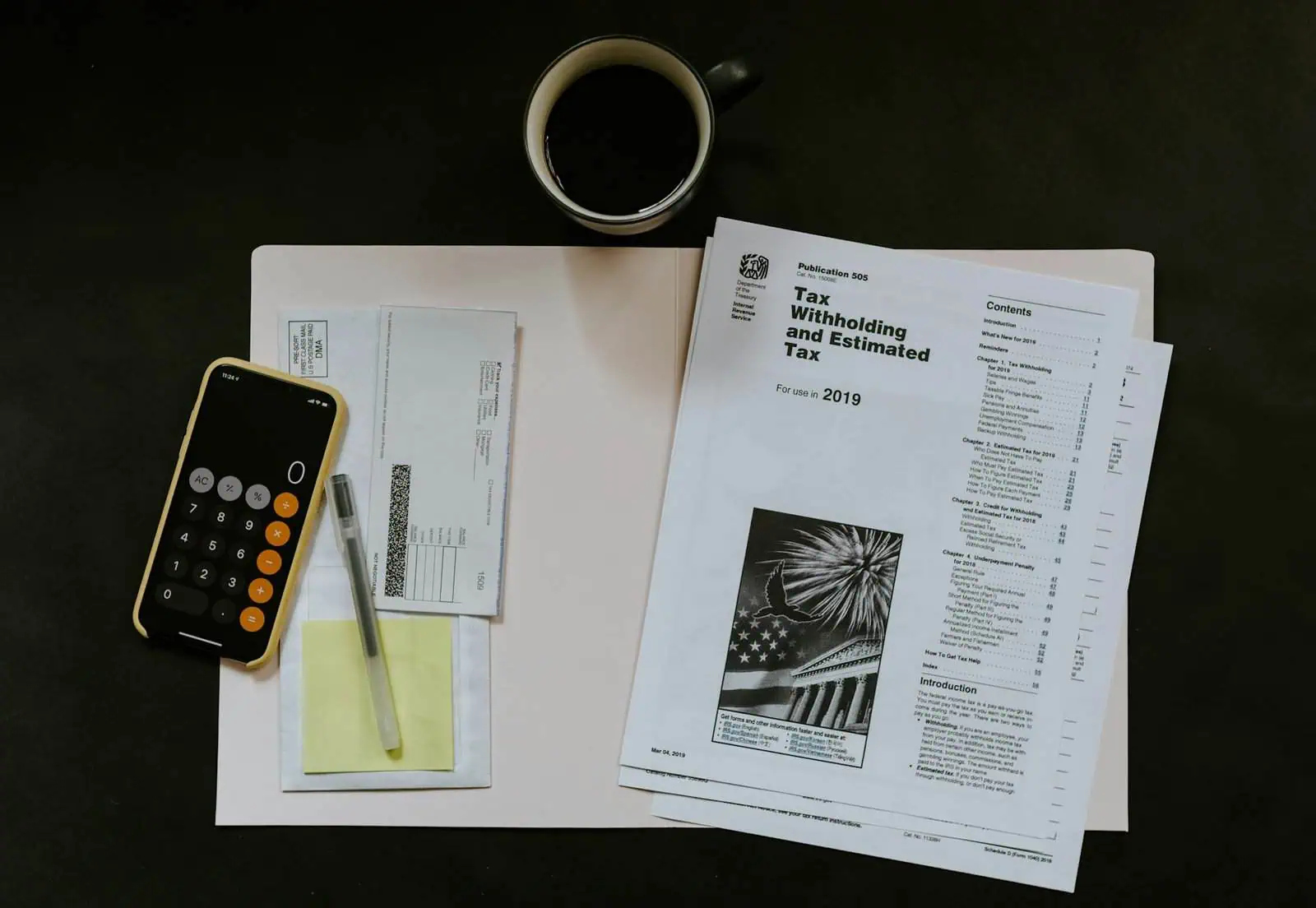 Calculator and financial documents on desk with coffee and tax papers.