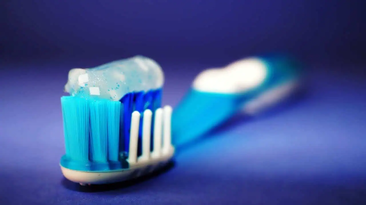 Blue toothbrush with toothpaste on bristles, close-up shot.