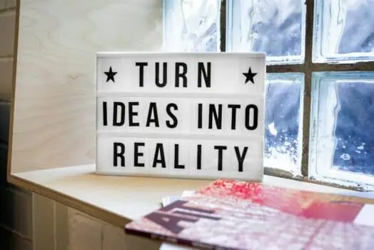 Optimise your ideas with this motivational lightbox sign displayed on a wooden surface near a frosted glass window. Perfect for inspiring creativity, innovation, and positive thinking in a modern workspace.
