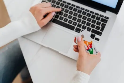 A person using a laptop and holding a credit card to make an online payment, highlighting secure online shopping and digital banking services.