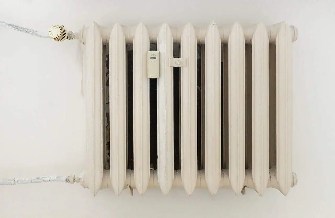 Radiator with thermostat on a white wall, central heating system.