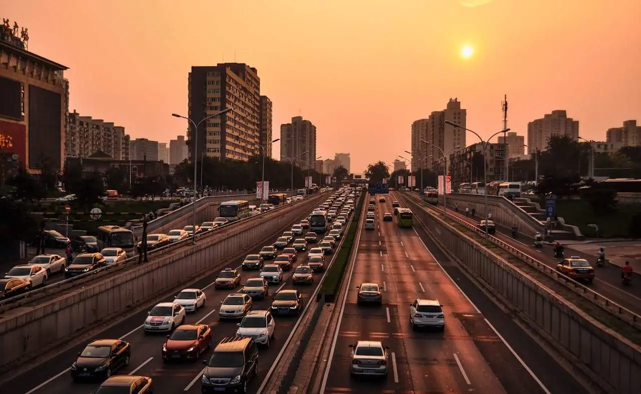 Congested city traffic during sunset in urban environment, with high-rise buildings and busy roads.