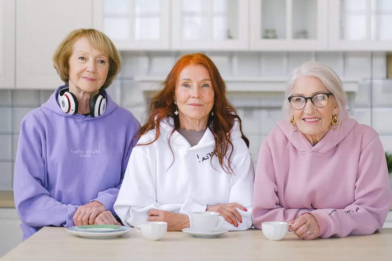 Empowered older women enjoying social time together in a bright, modern kitchen, highlighting community and wellbeing for seniors.