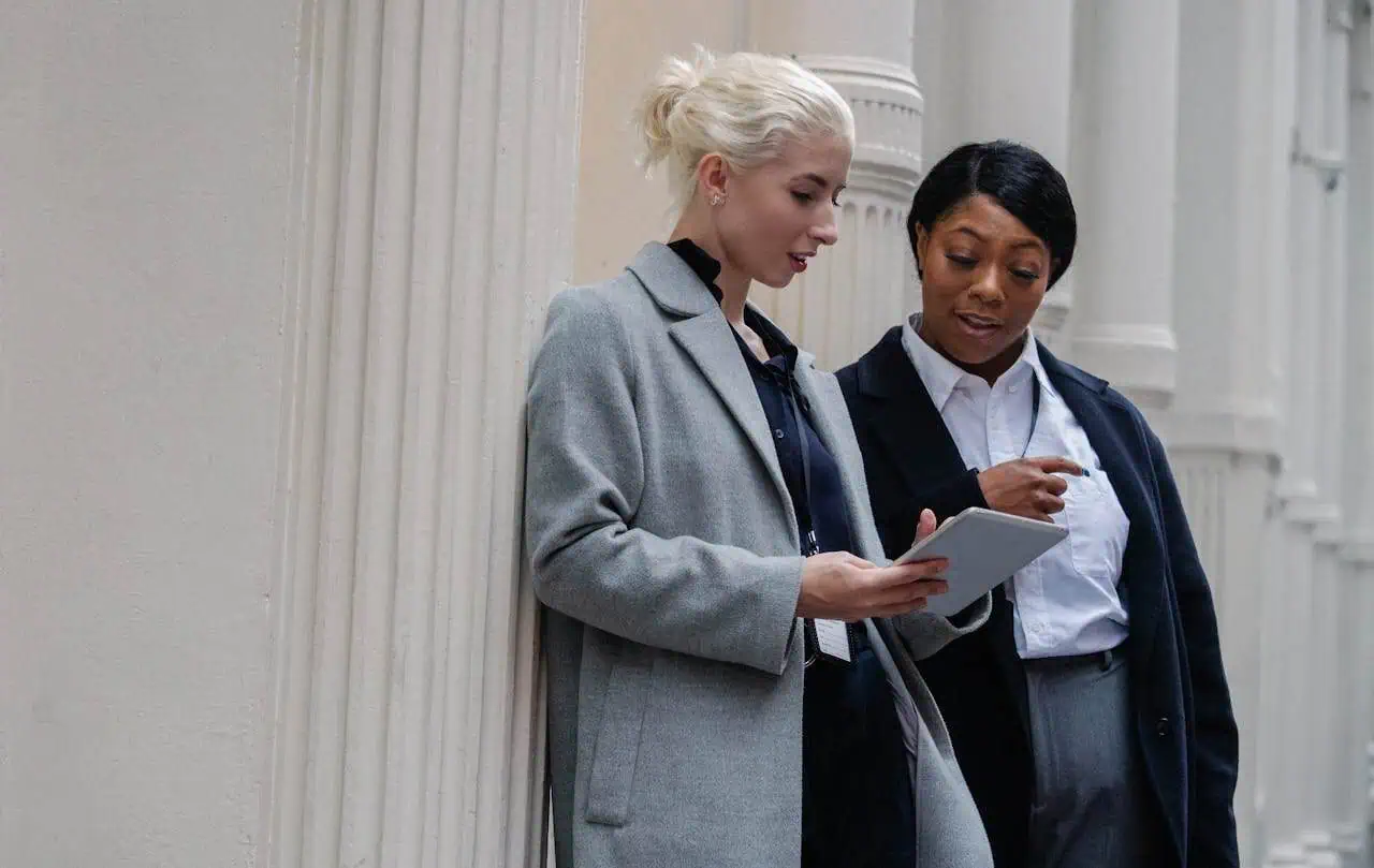 Professional women collaborating on a tablet in a government or corporate building, promoting women's empowerment, diversity, and professional development in the workplace.