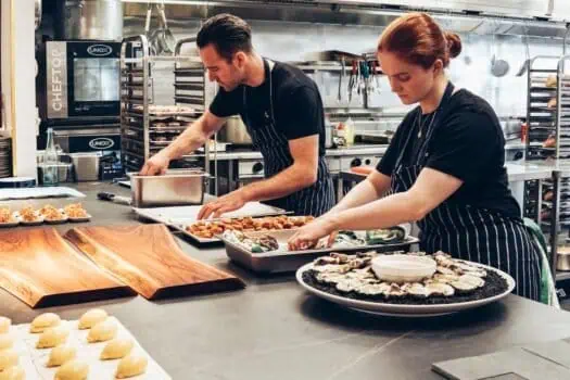 Chefs preparing seafood dishes in a professional kitchen, showcasing culinary skills and food presentation. Focus on seafood cooking, professional chefs, and kitchen environment for SEO.