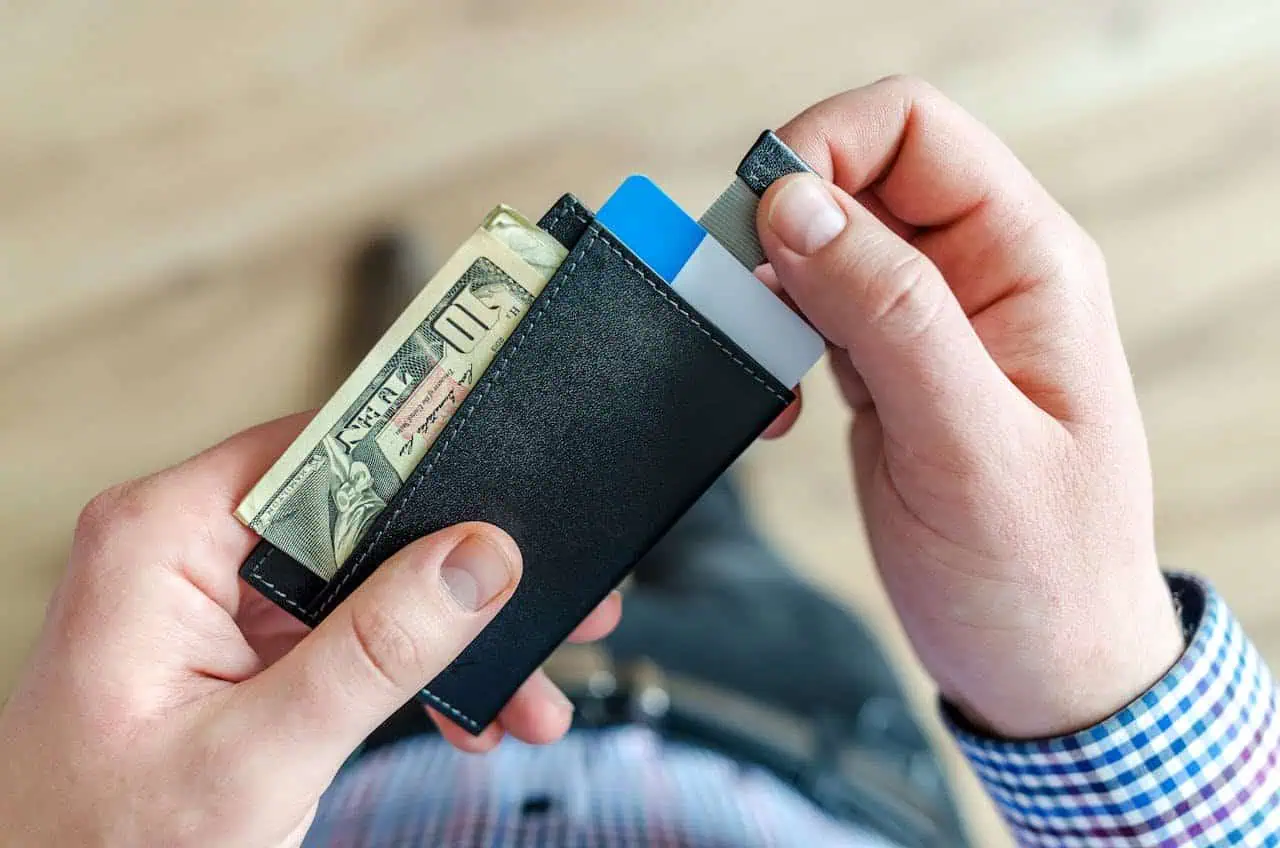 Cash wallet with money, credit cards, and ID holder, close-up of a person's hands holding a black leather wallet, financial management, personal finance, credit card security.
