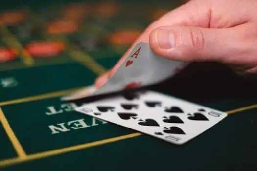 Playing card game with an ace of hearts on a roulette table in a casino setting.