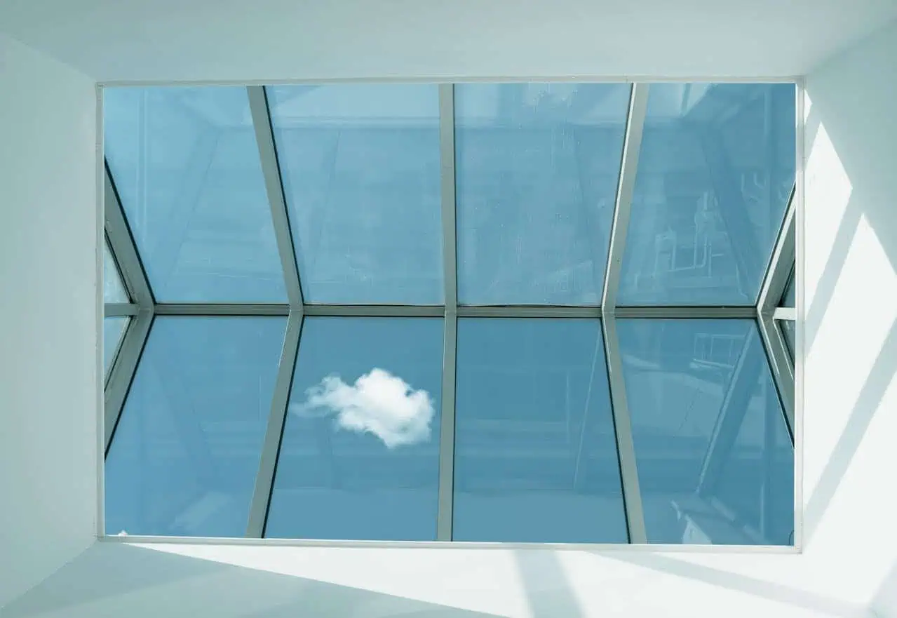 Beautiful modern skylight window with clear glass panels showcasing a blue sky and a small cloud, enhancing natural light and architectural aesthetic.