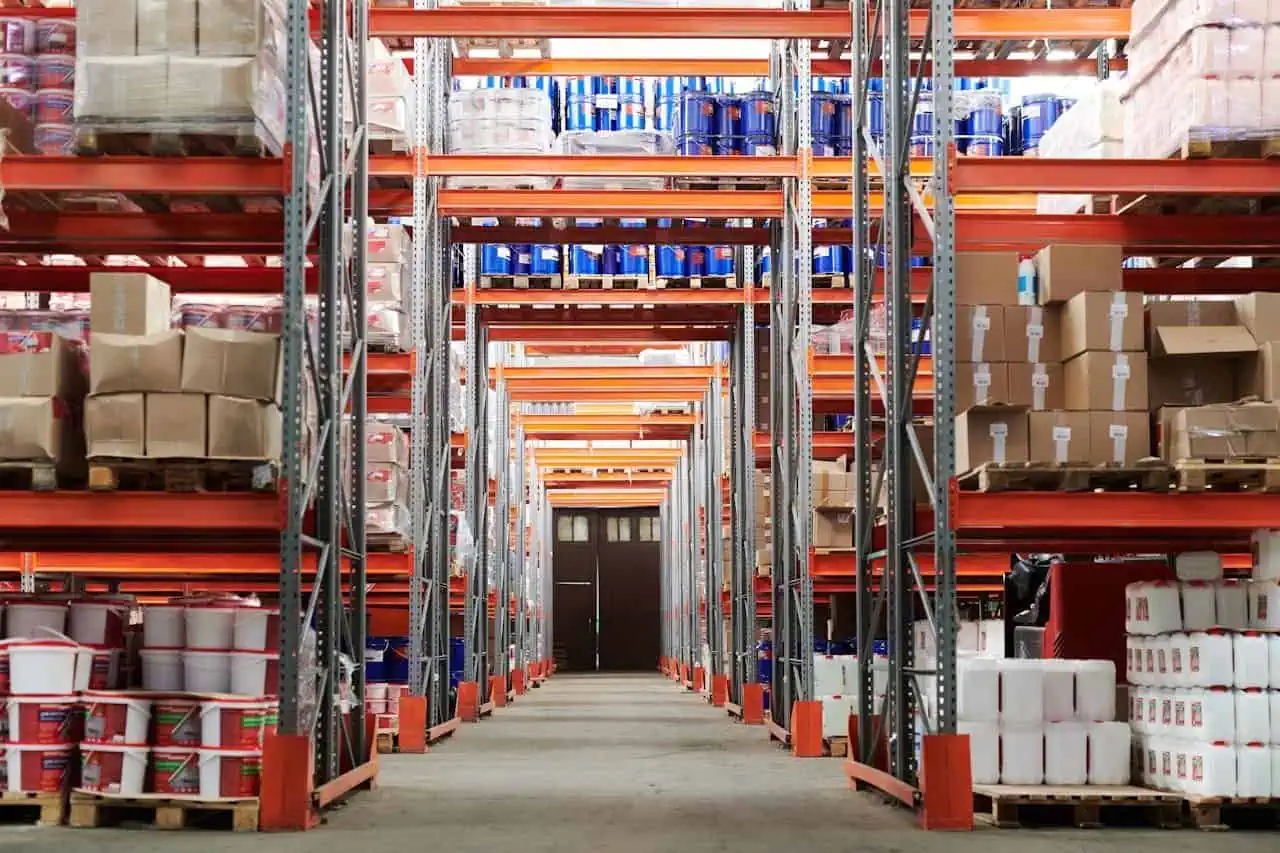 Prowess warehouse shelving with various building materials and supplies stored on high orange metal racks, showcasing efficient storage solutions for construction and industrial needs.