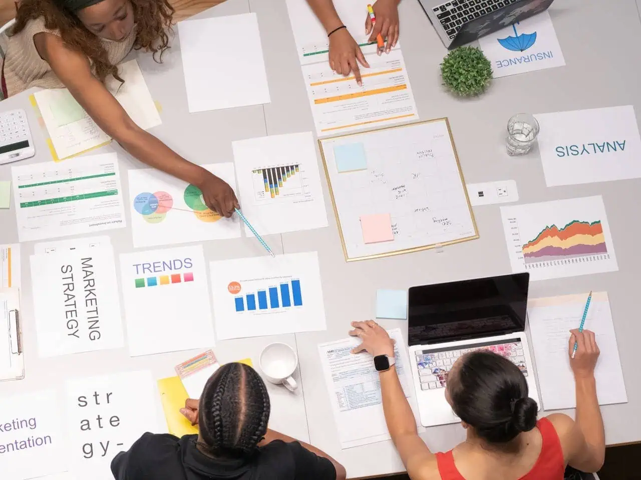 Business meeting with colourful charts and graphs on the table, teamwork and strategy planning, data analysis, marketing strategies, collaborative work in a professional office setting.