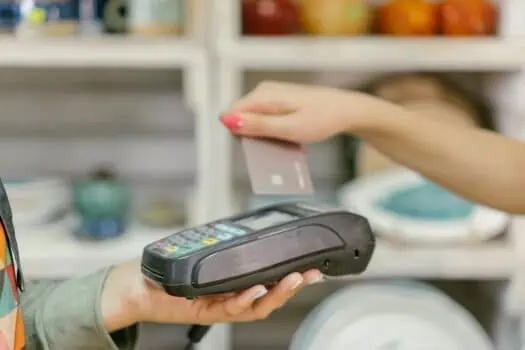 Contactless payment transaction at retail store, modern POS terminal with card reader, person using credit card for secure transaction, electronic payment system, shopping technology.