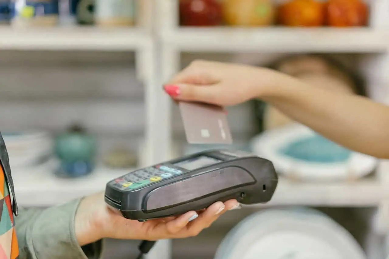 Contactless payment transaction at retail store, modern POS terminal with card reader, person using credit card for secure transaction, electronic payment system, shopping technology.
