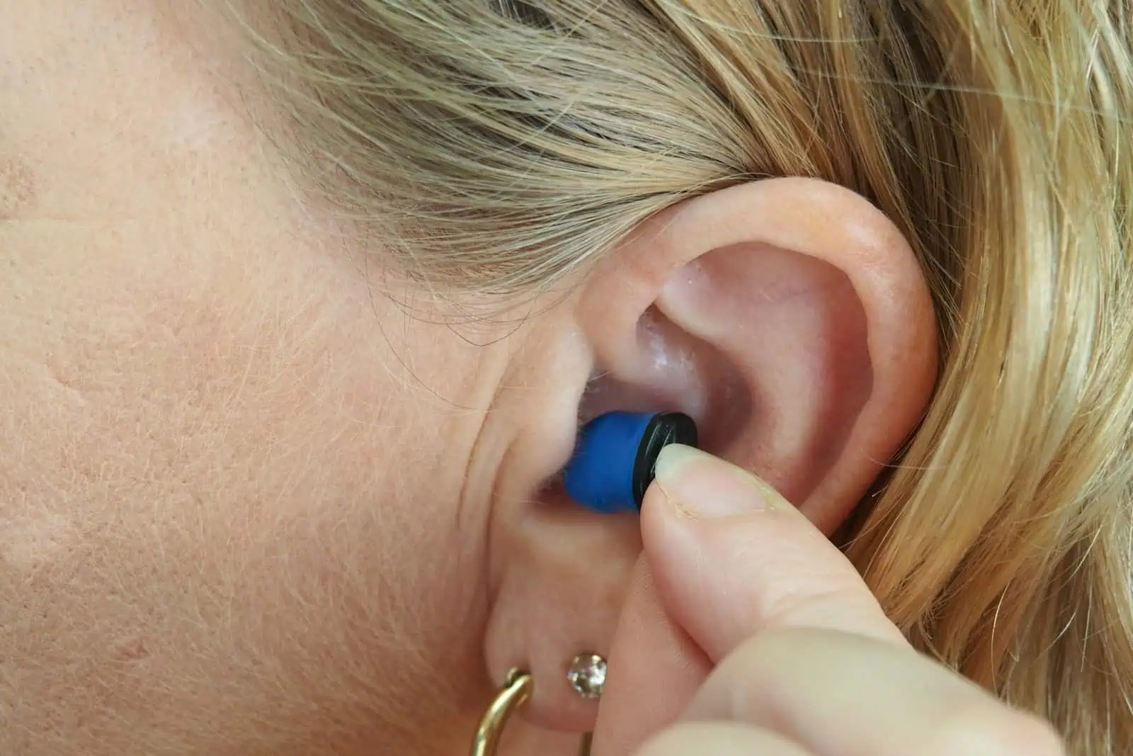 Hearing aid being inserted into a person's ear for improved hearing assistance and support.
