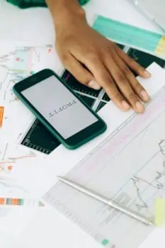 Bright analysis of financial data and stock charts for investors and traders with a smartphone displaying the Prowess logo, illustrating financial analysis and investment management.