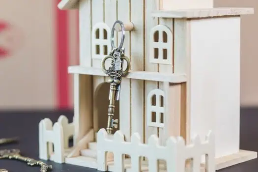 Key-shaped lock on miniature wooden house, symbolising home security and safety, with a focus on property security solutions from Prowess UK.