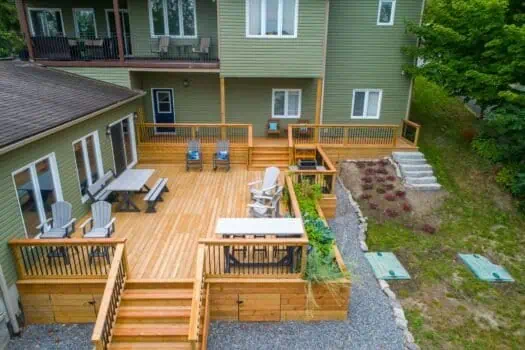 Beautiful multi-level wooden deck and patio area in backyard with outdoor furniture and garden space, perfect for relaxing and entertaining.