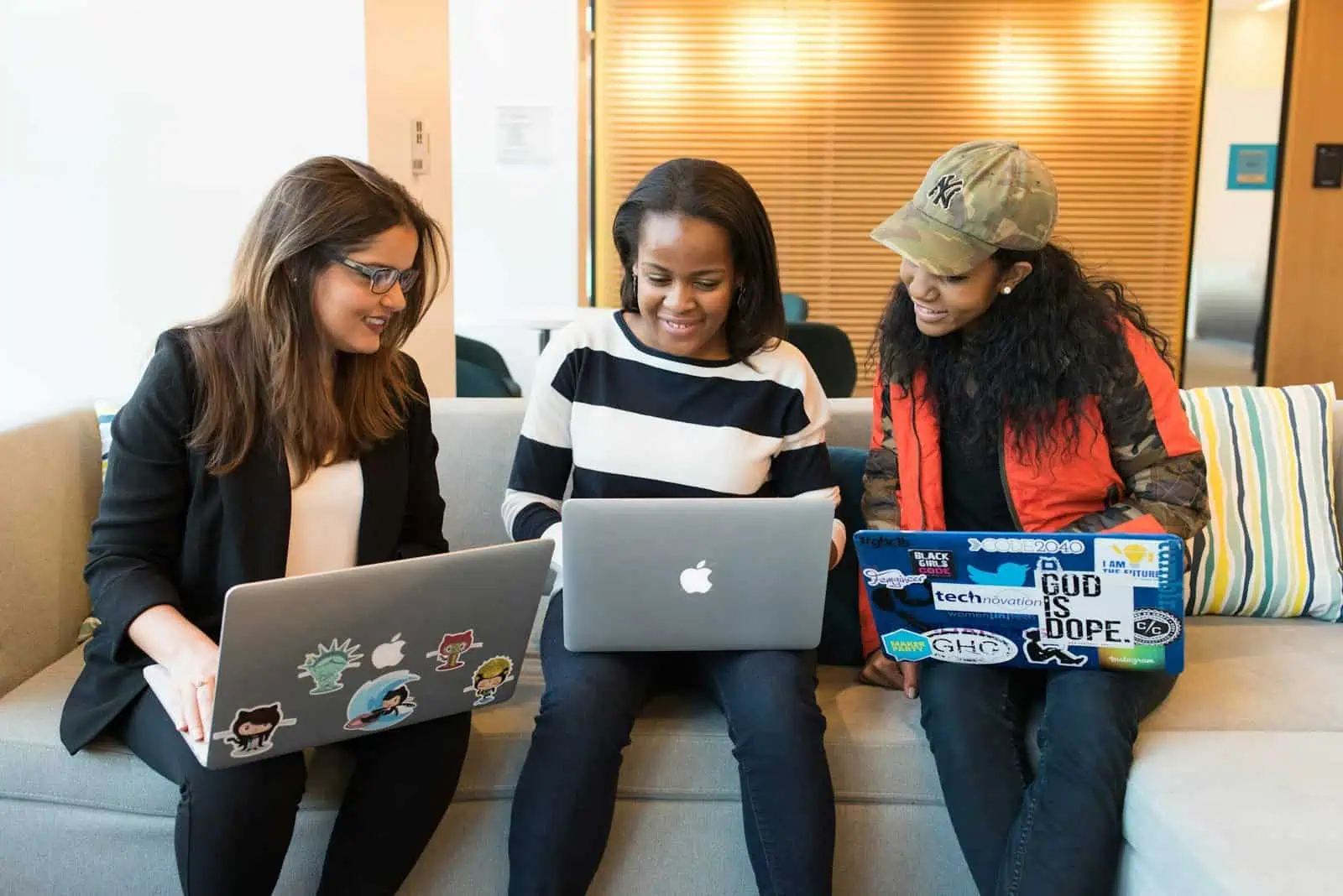 Diversity group of three women working together on laptops in a modern office environment.