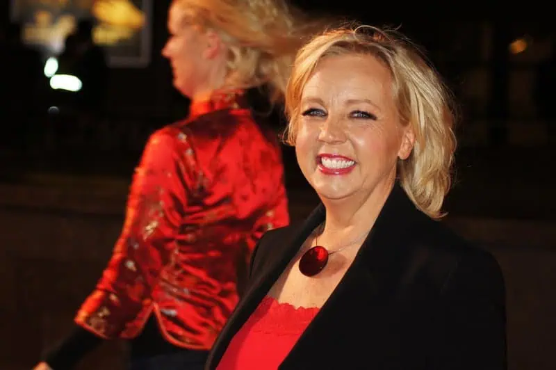 Confident blonde woman smiling at an evening event, dressed in black and red, showcasing empowerment and positivity.