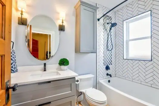Modern bathroom with bathtub, vanity, and contemporary decor, featuring a herringbone tiled shower area and elegant lighting for a stylish, functional space.