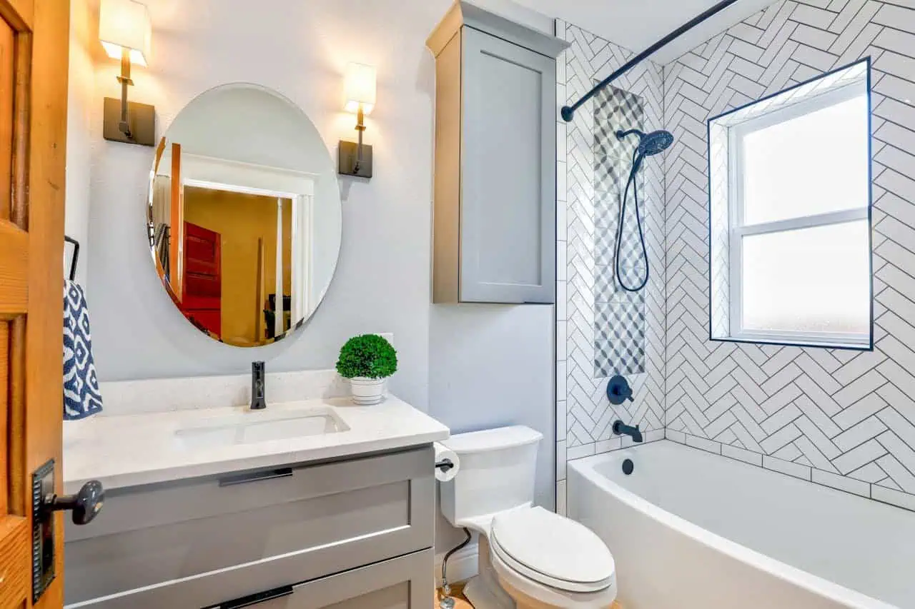Modern bathroom with bathtub, vanity, and contemporary decor, featuring a herringbone tiled shower area and elegant lighting for a stylish, functional space.