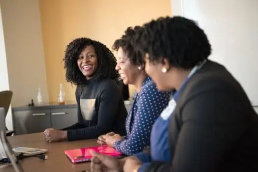 Motivated diverse women smiling and engaging in a professional meeting at the Prowess organisation for women's empowerment and development.