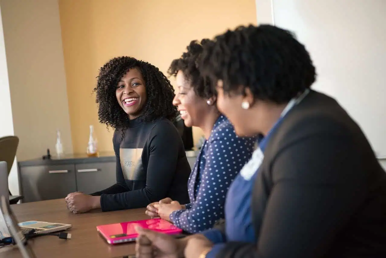 Motivated diverse women smiling and engaging in a professional meeting at the Prowess organisation for women's empowerment and development.