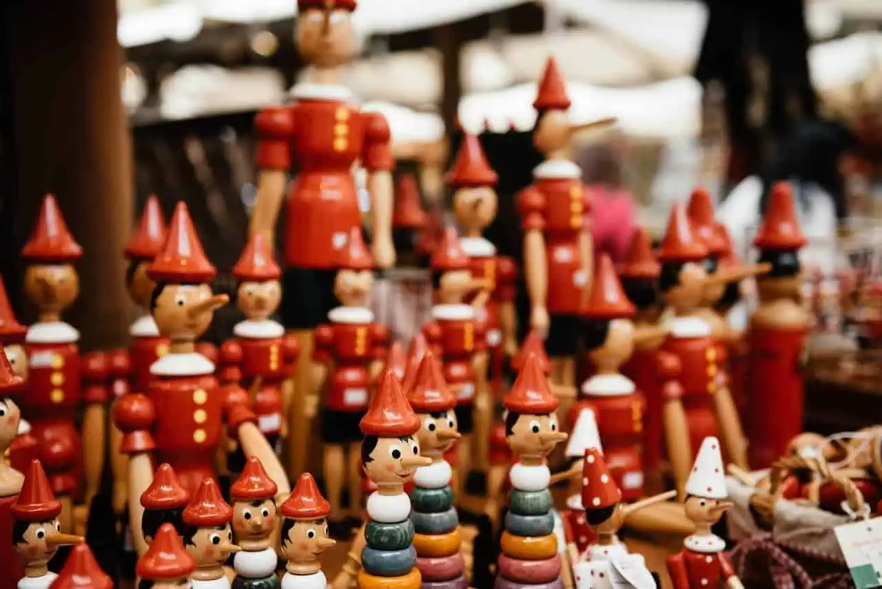 Colourful wooden toy soldiers and Pinocchio figures displayed at a market stall, showcasing handcrafted toys ideal for collectors and children.