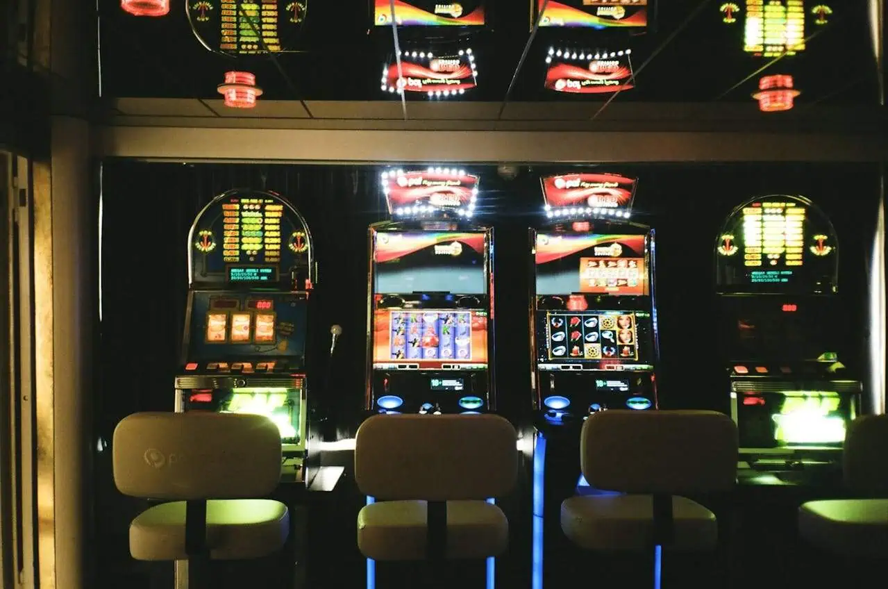 Slot machines in a casino setting, illuminated with colourful lights and digital displays, creating an engaging gambling environment. Perfect for casino gaming, entertainment, and luck-themed content.