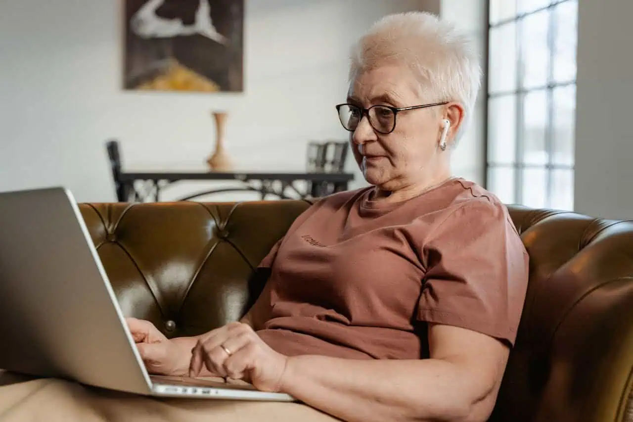 Accessible and engaging elderly woman using a laptop at home, representing digital inclusion and support for seniors, which complements Prowess' mission of empowering individuals through education and technology.