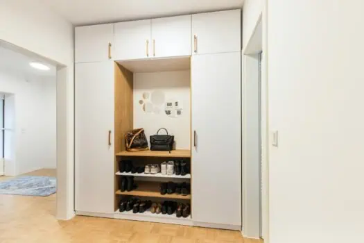 Organised entrance hallway shoe storage with white and wooden cabinets, shoes, bags, and mirror, modern home interior, minimalistic design, practical home organisation, contemporary furniture, Prowess.