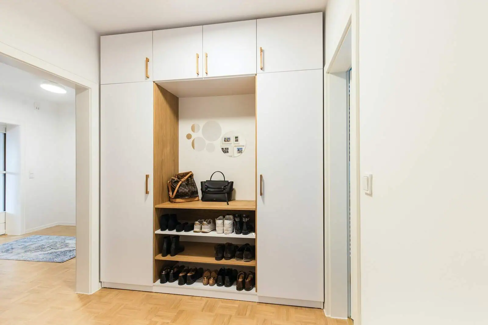 Organised entrance hallway shoe storage with white and wooden cabinets, shoes, bags, and mirror, modern home interior, minimalistic design, practical home organisation, contemporary furniture, Prowess.