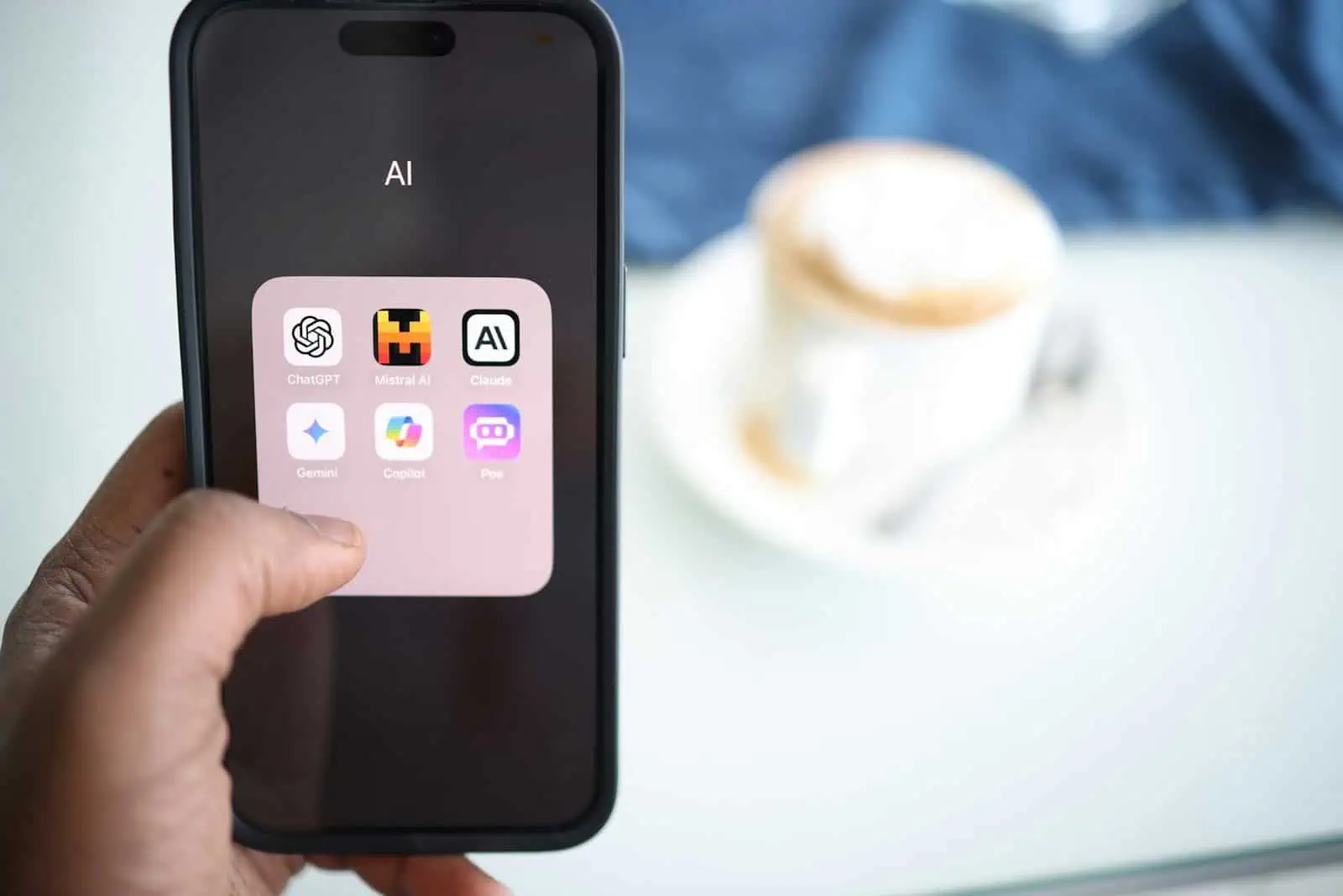 AI icons on smartphone screen, focusing on AI applications and chatbots, with a blurred tea cup in background, representing technology and AI innovation.