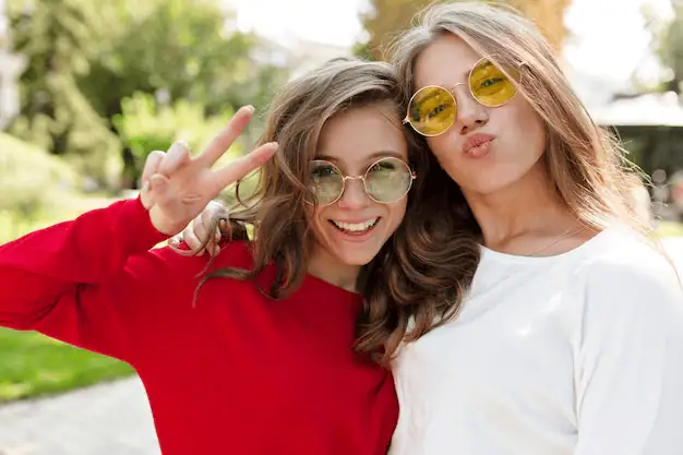 Bright young women wearing colourful sunglasses enjoying sunny day outdoors, symbolising fun, friendship, and youthful energy. Perfect for youth engagement and outdoor activities.