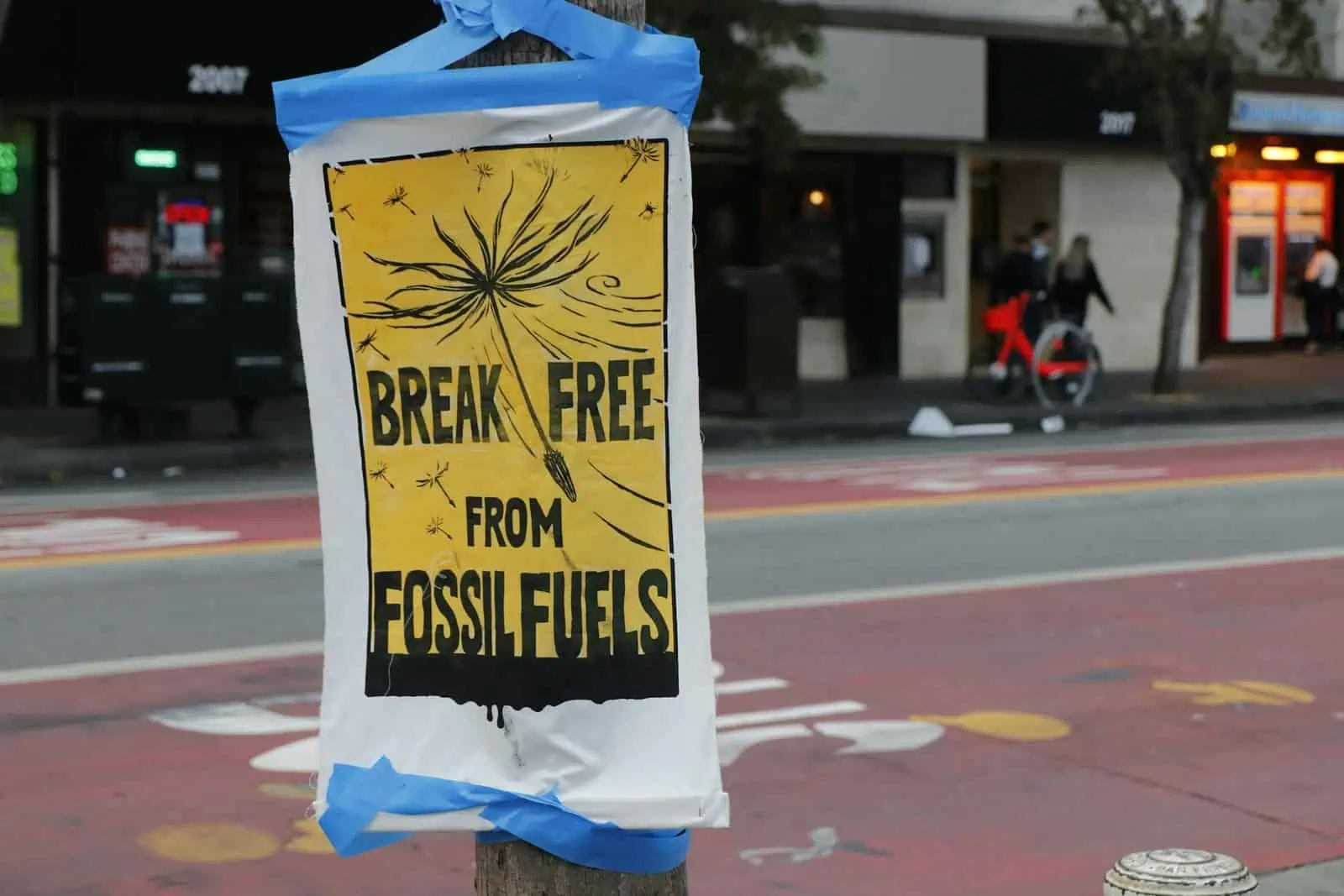 Flickering protest sign on a city street addressing climate change and fossil fuel reduction.