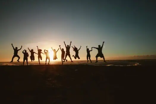 Jumping children silhouette at sunset on the beach, promoting youth empowerment, community activity, and fun outdoor recreation with a focus on social inclusion and well-being.