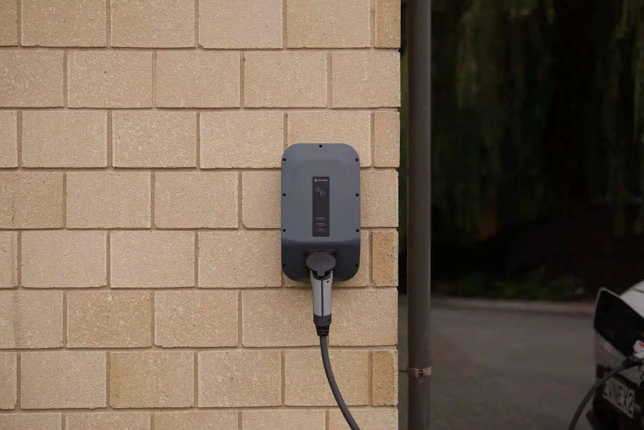 Electric vehicle charging station on a brick wall, eco-friendly car charging point for sustainable transportation, Prowess EV charger for electric car eco-charging solutions.