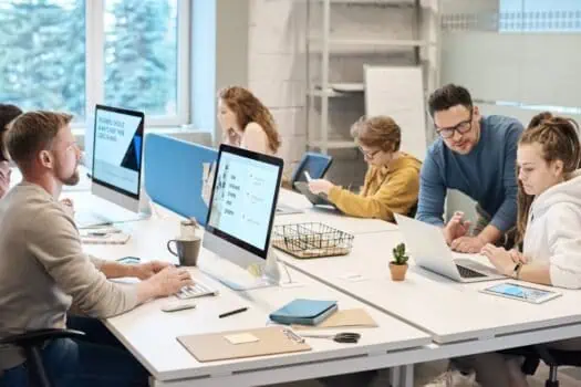 Innovative team collaborating in a modern office workspace, working on computers and laptops, representing teamwork, productivity, and digital skills.
