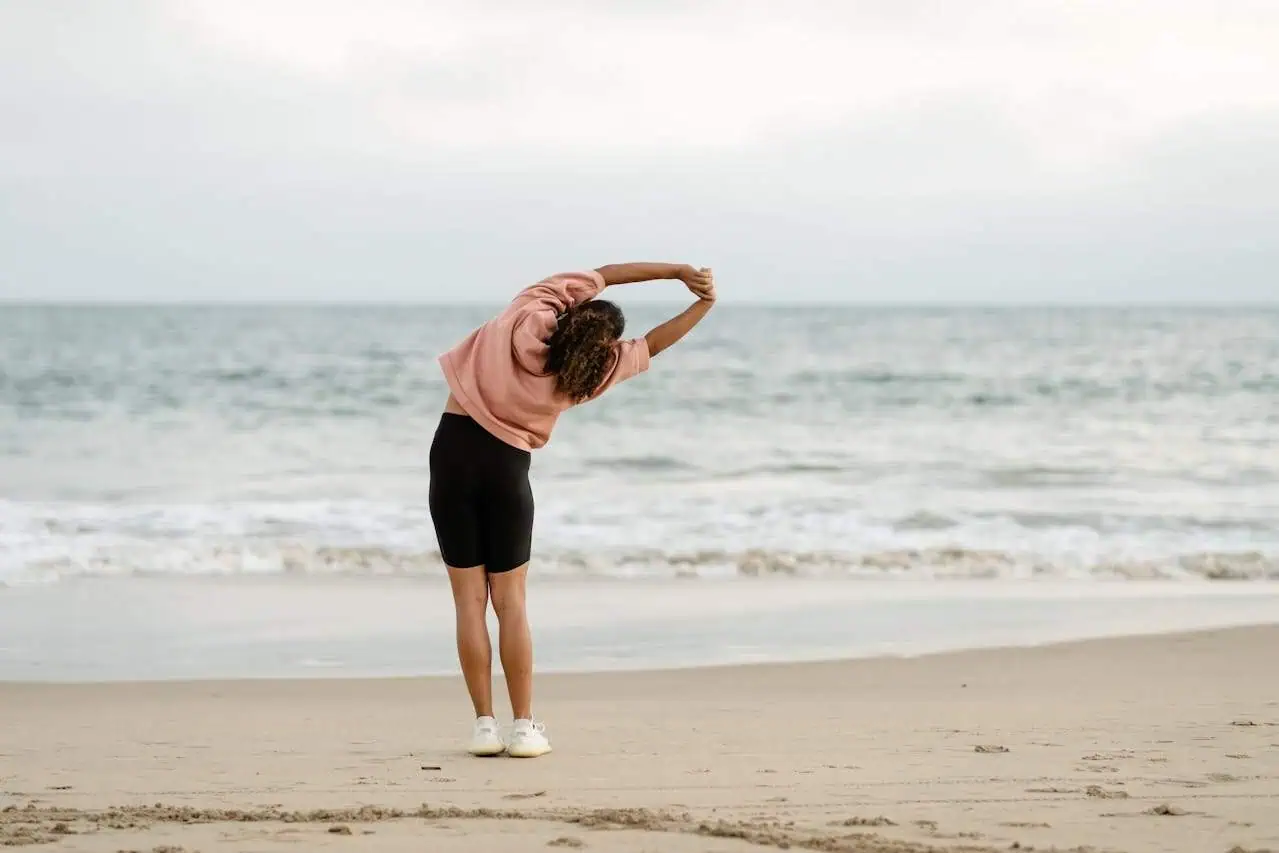 Stretching exercises on the beach, promoting mental health and well-being, with a focus on mindfulness and physical activity for mental health benefits.