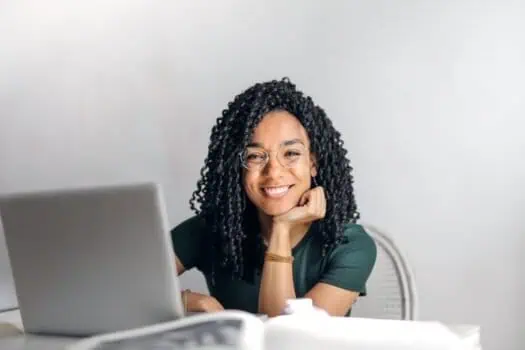 Woman smiling at work with laptop, diverse professional woman, modern office environment, engaging with technology, confident and happy, female entrepreneur, professional workspace, friendly businesswoman, productivity, empowerment, female empowerment, success, positive attitude, working remotely, online work, digital workplace, career development, professional growth, workplace diversity, female leadership, innovation, empowerment.